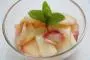 Fruit salad of peeled peaches in syrup with rum, mint and lime.