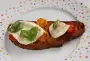 Tomato and herb bruschetta, baked with a slice of mozzarella.