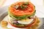 Stack of sliced tomato, avocado, onion, egg and anchovy, pressed in a ring mould.