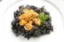 Shelled mussels served on a bed of rice with squid ink.